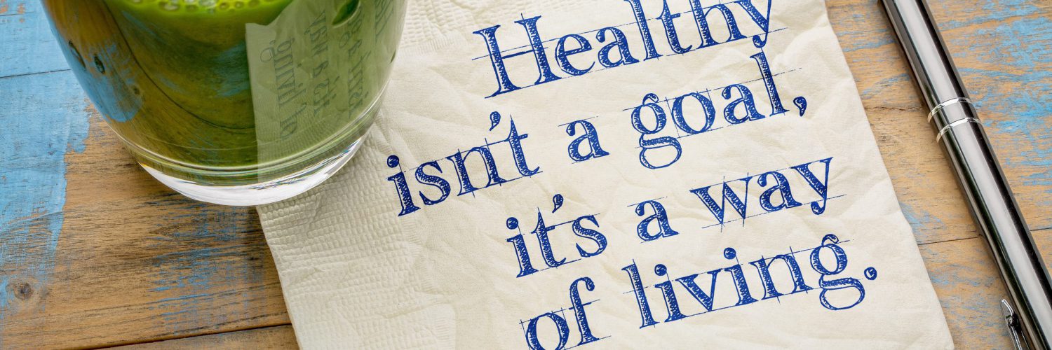 Healthy is not a goal, it is a way of living advice or reminder - handwriting on a napkin with a glass of fresh, green, vegetable juice