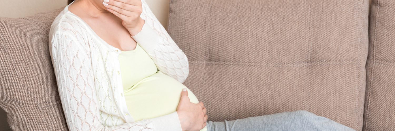 Pregnancy Morning Sickness. Pregnant Woman Having Nausea Feeling Bad in Sofa at the Home.