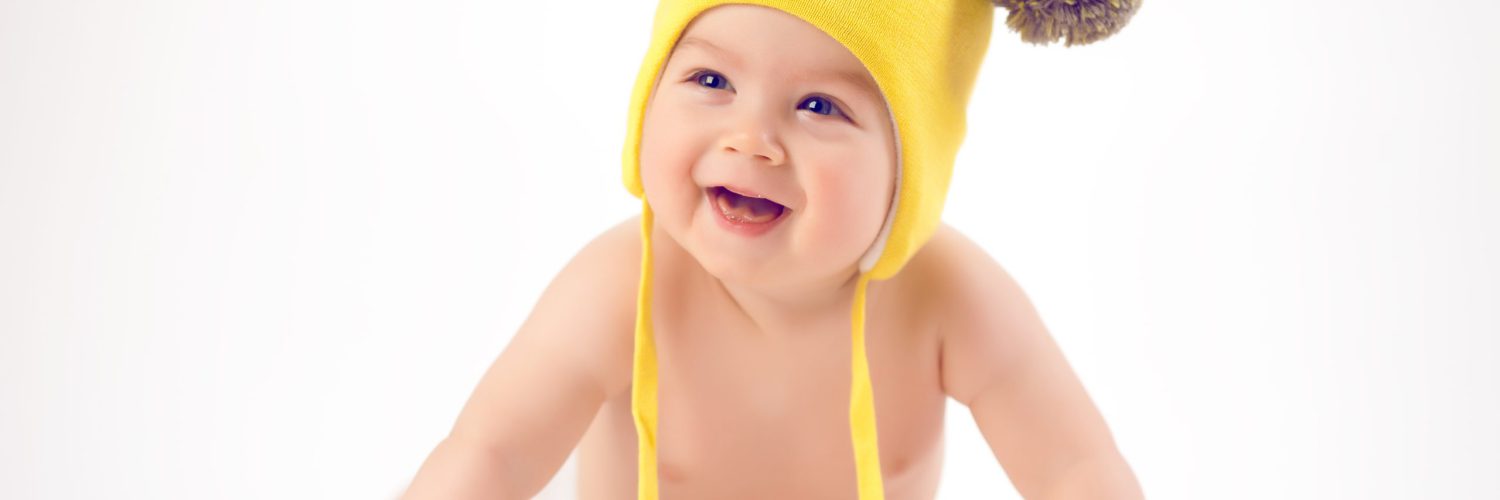 Baby in yellow winter hat lying on the floor